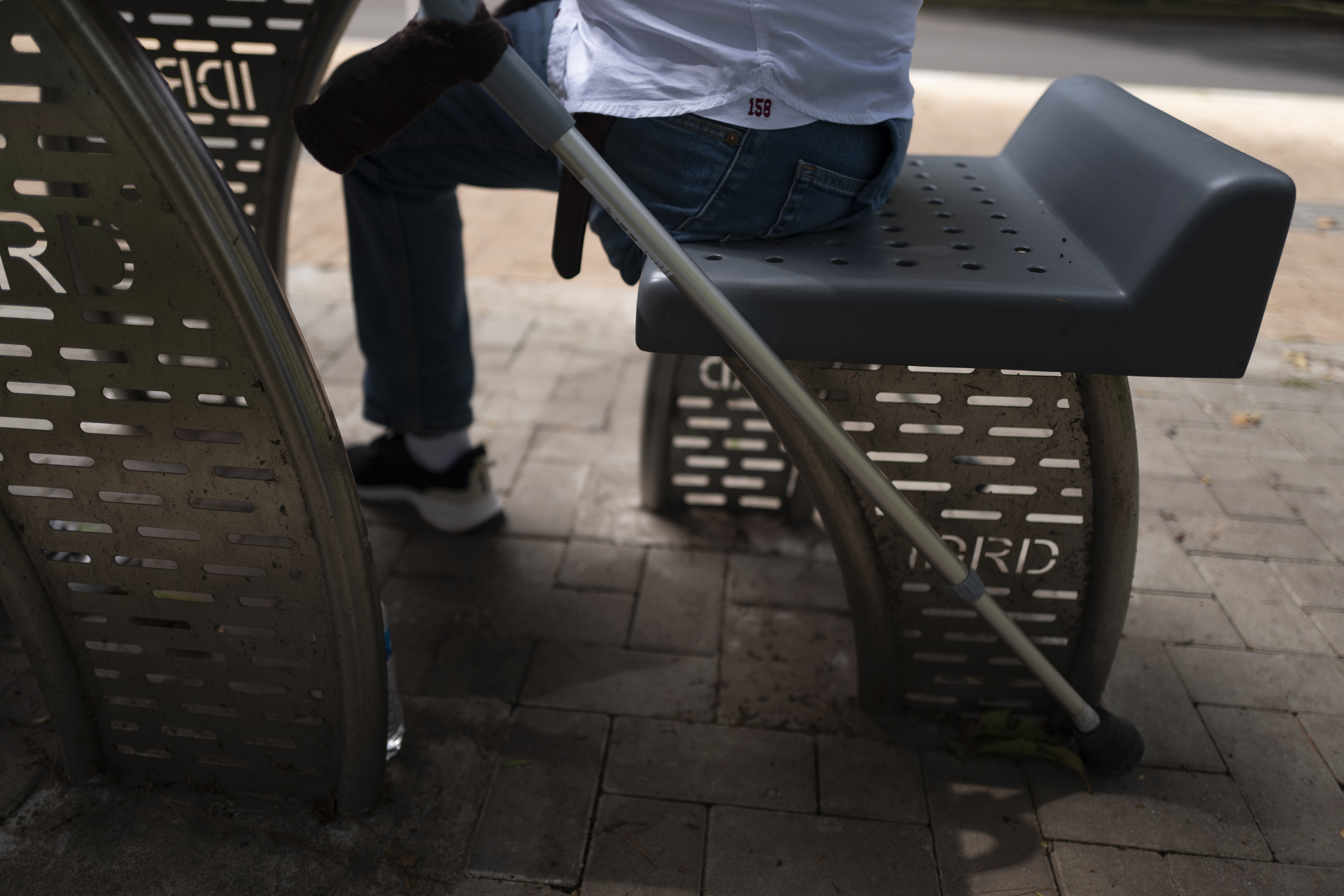 man seated at a park bench showing torso down view of amputated leg