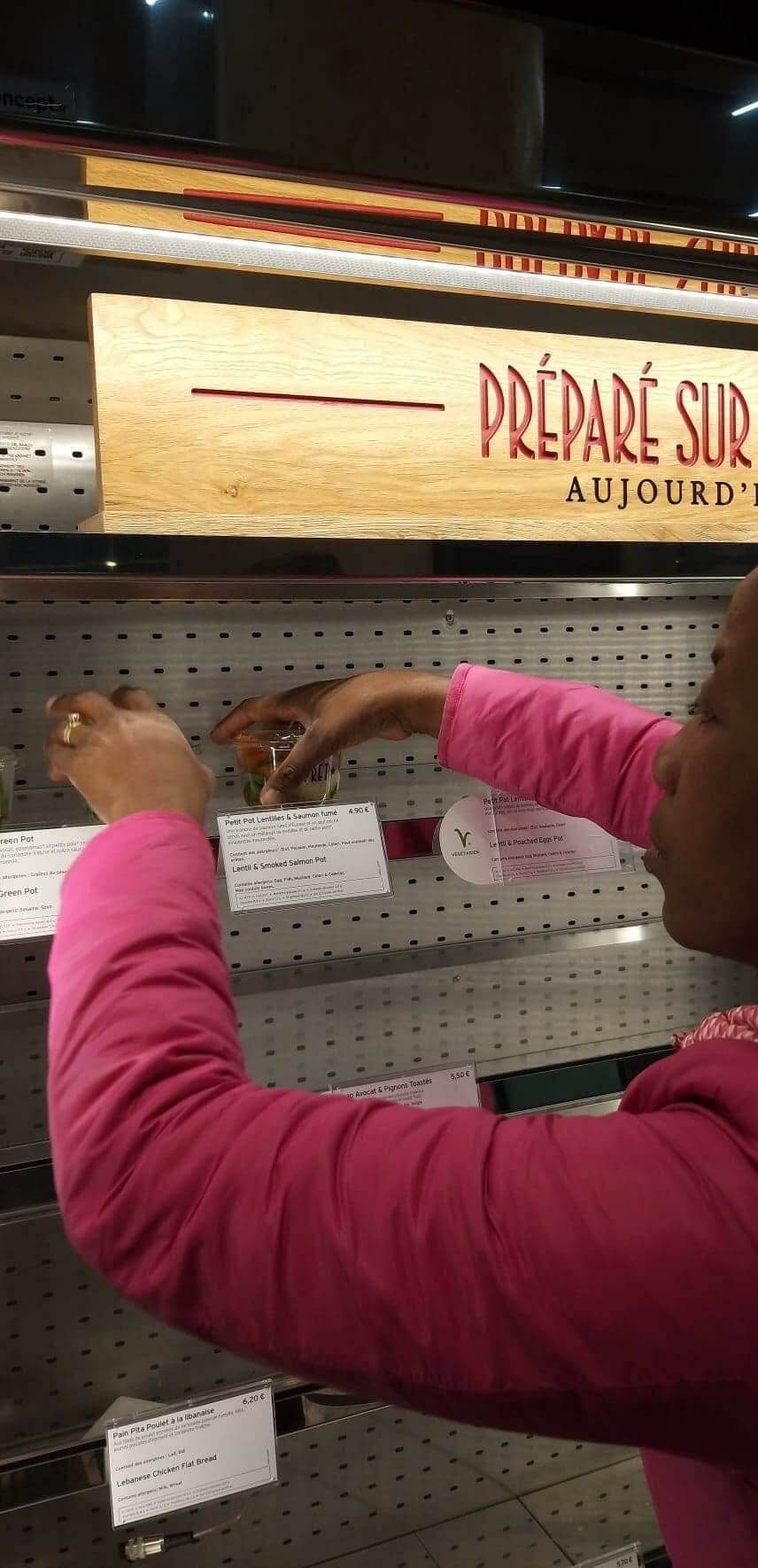 Georgette reaches into the display shelves to gather the donated food.